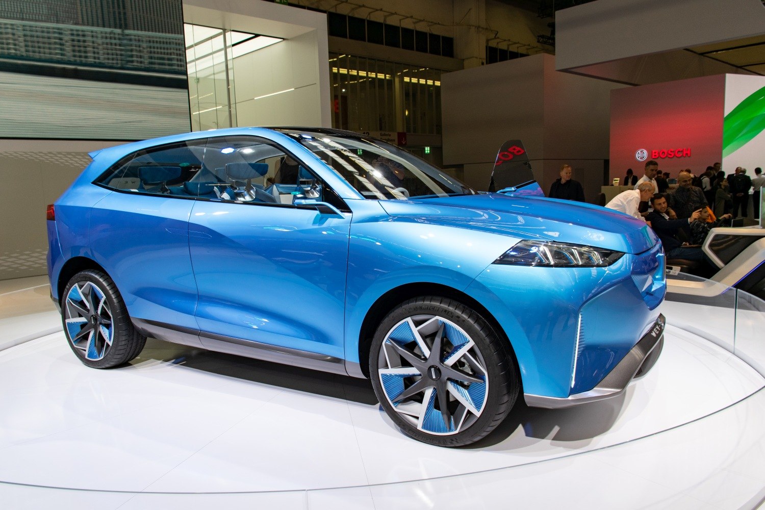 Blue electric SUV with futuristic multi-spoke wheels and sleek LED headlights