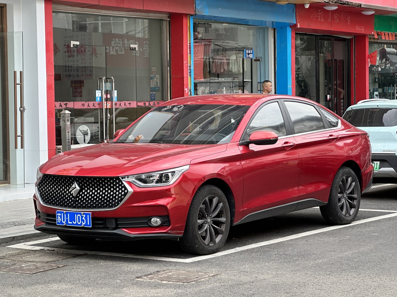 Large grille and LED headlights on red sedan side and front profile