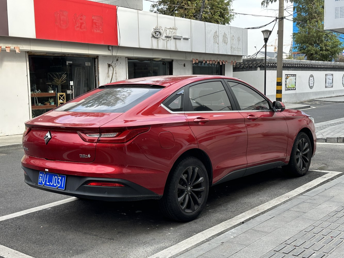 Rear and side profile of red sedan with sleek taillights and black alloy wheels