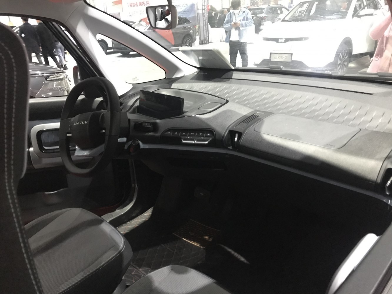 Minimalistic dashboard and steering wheel design in a compact electric microcar interior