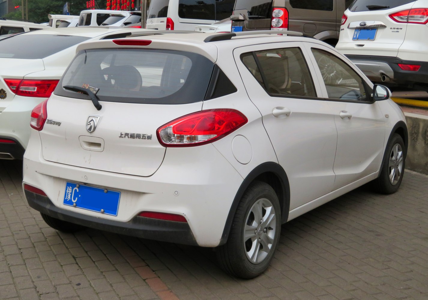 Rear view of white compact hatchback with prominent taillights and roof rails