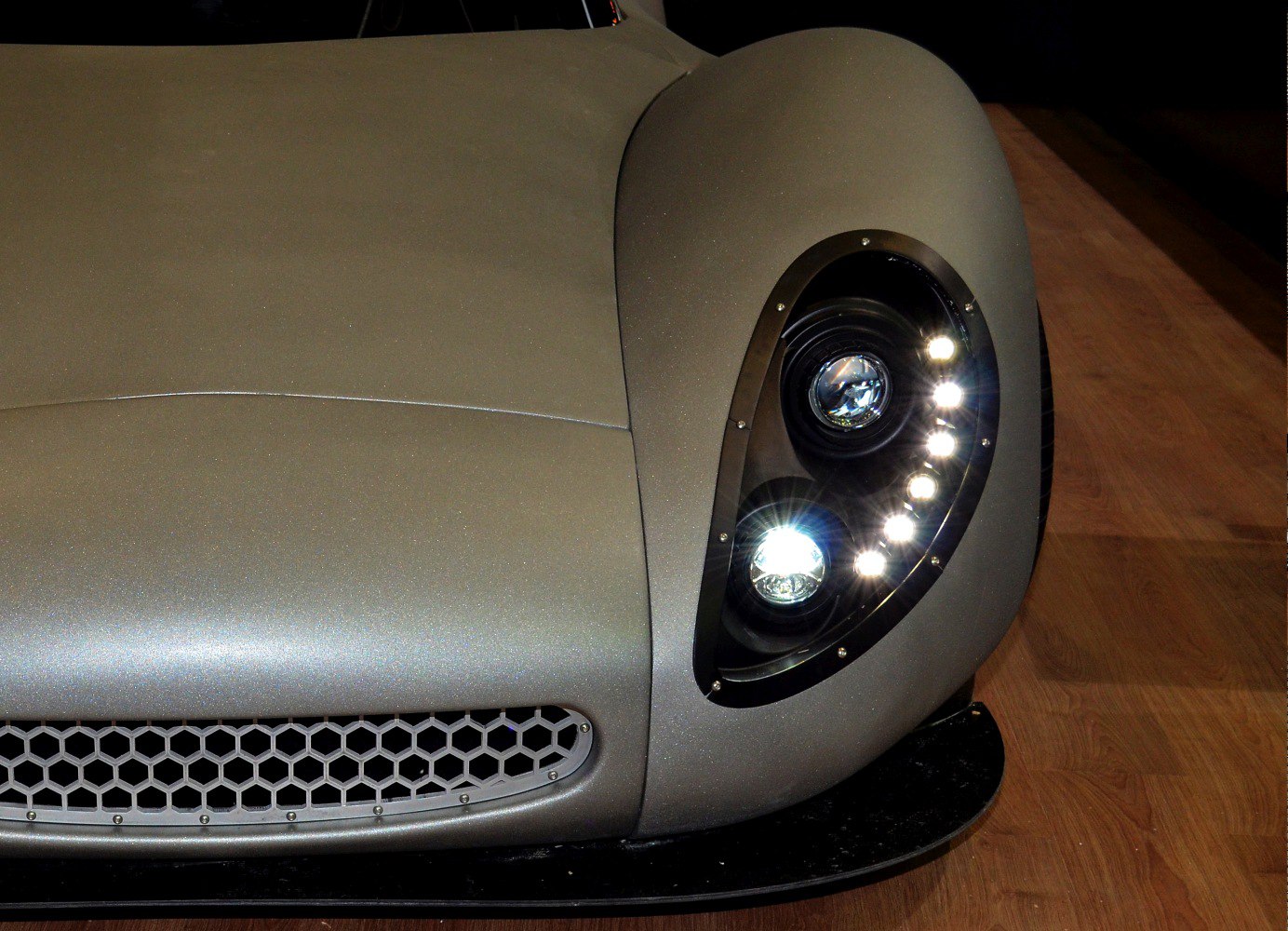 Close-up of sleek headlight and honeycomb front grille