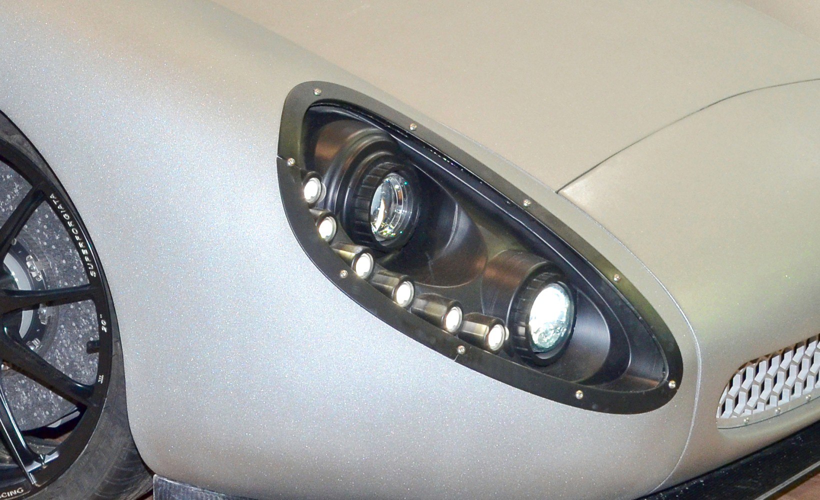 Close-up of unique headlamp and sporty wheel design on a concept vehicle