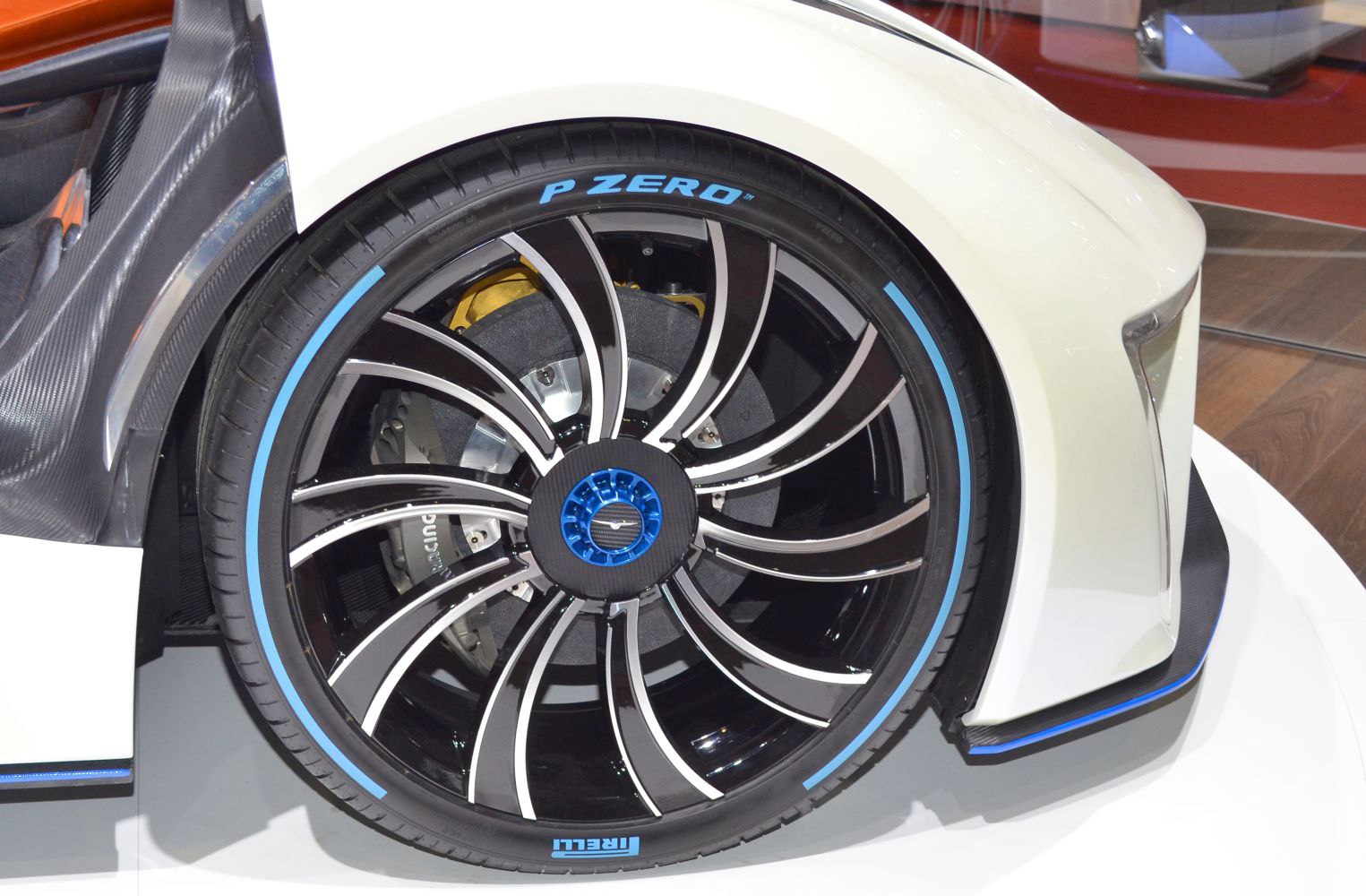 Black alloy wheel with blue accents and Pirelli P Zero tire on a white vehicle.