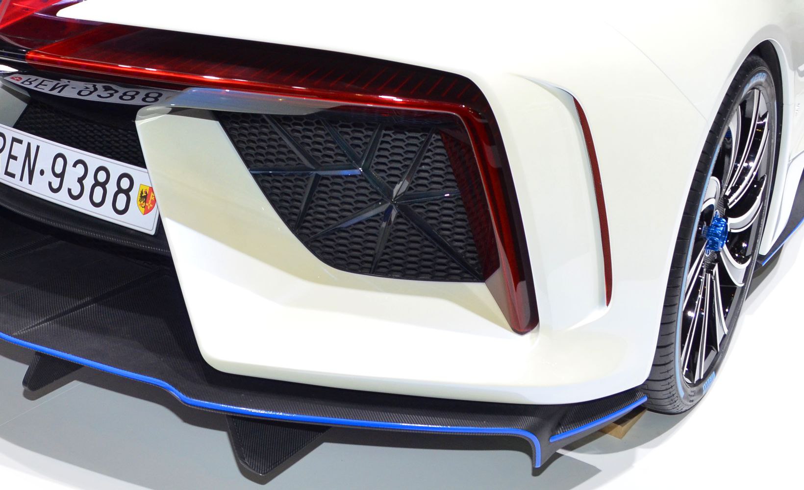 Rear tail light, diffuser, and wheel close-up on a white sports car