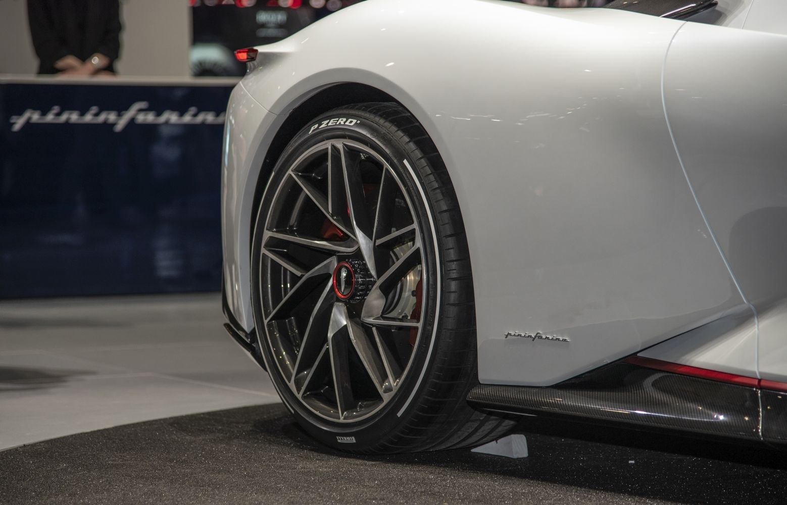 Close-up of rear wheel with alloy rim and side skirt with carbon fiber accents.