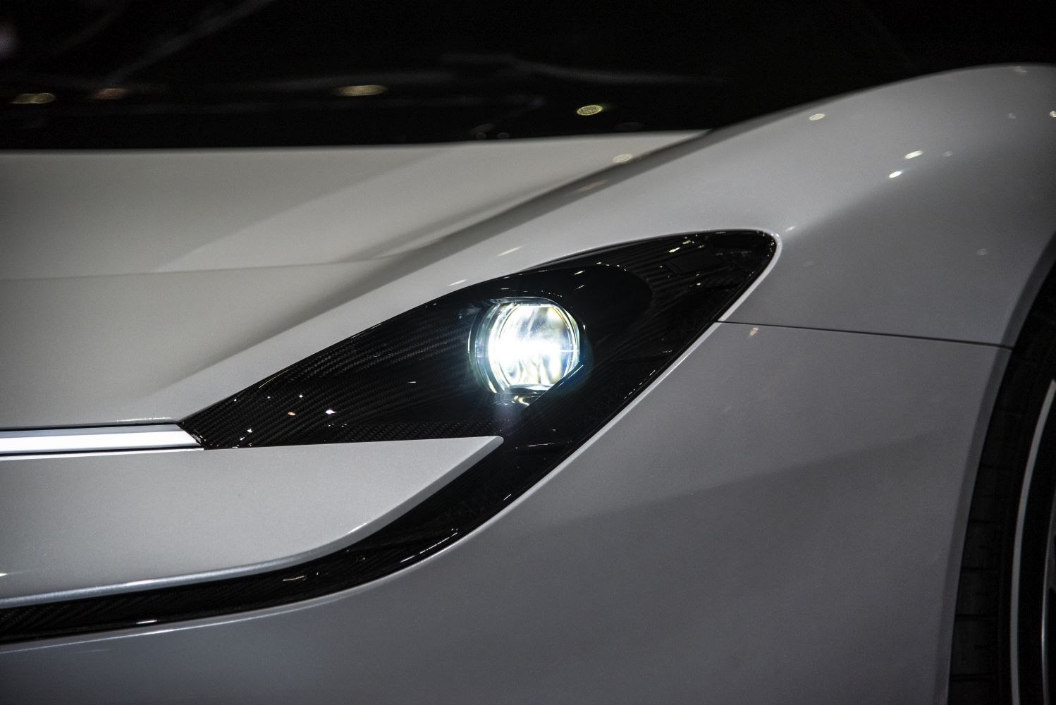 Close-up of a sleek headlight and carbon fiber front fender detail