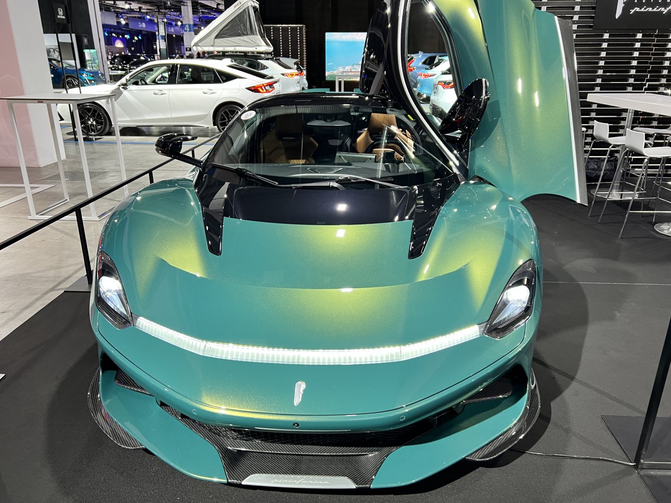 Front view of sleek sports car with scissor door open and LED headlights