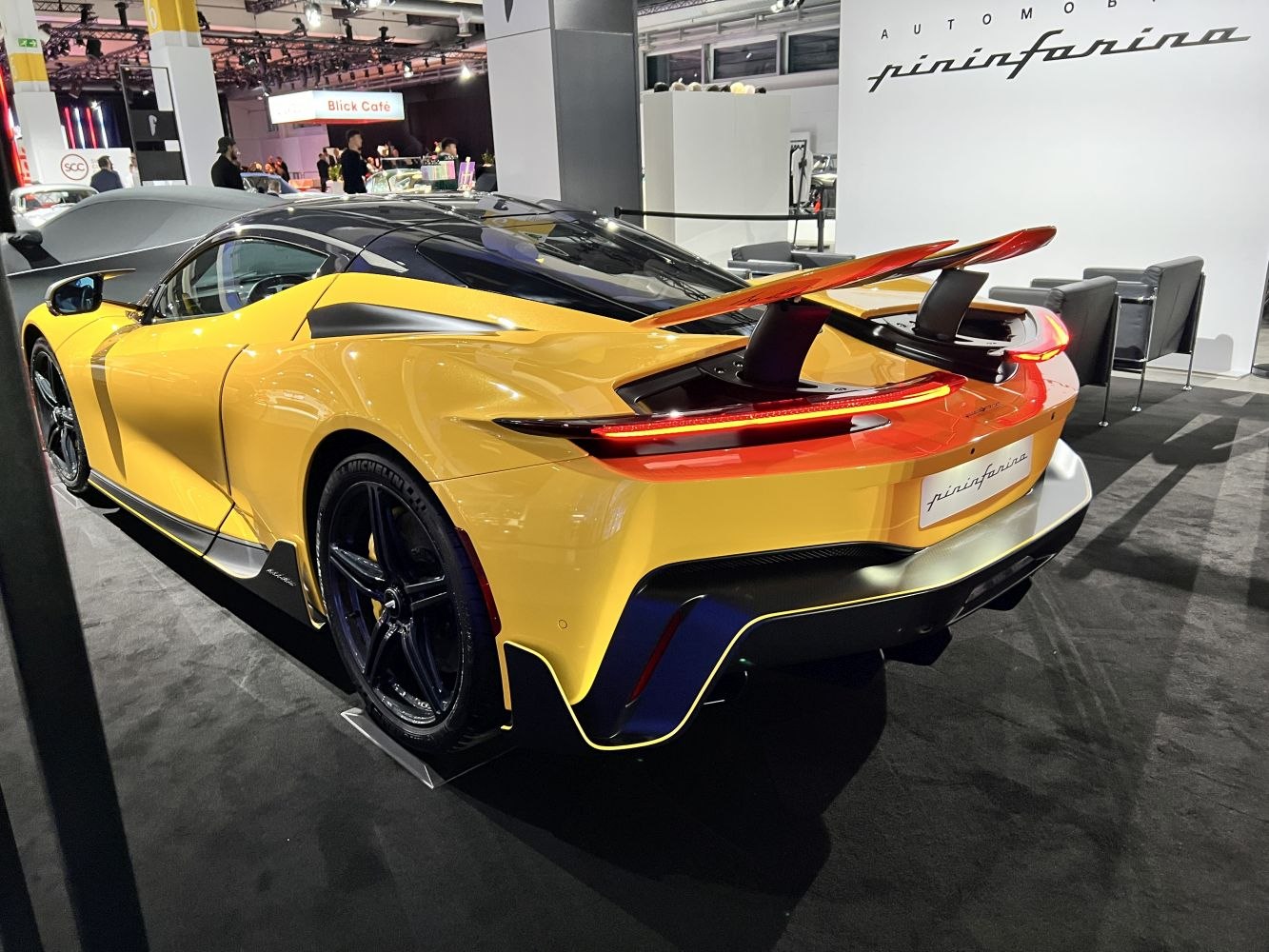 Rear view of a sleek sporty yellow vehicle with raised rear spoiler.