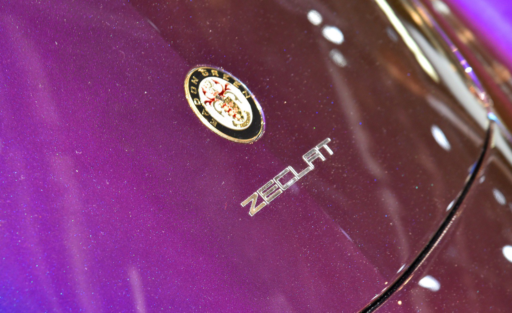 Close-up of car badge and metallic purple paint