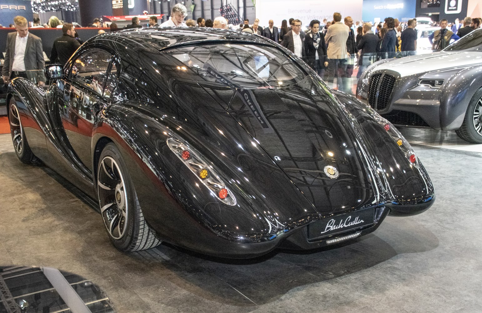 Sleek teardrop-shaped rear with integrated taillights on glossy black coupe
