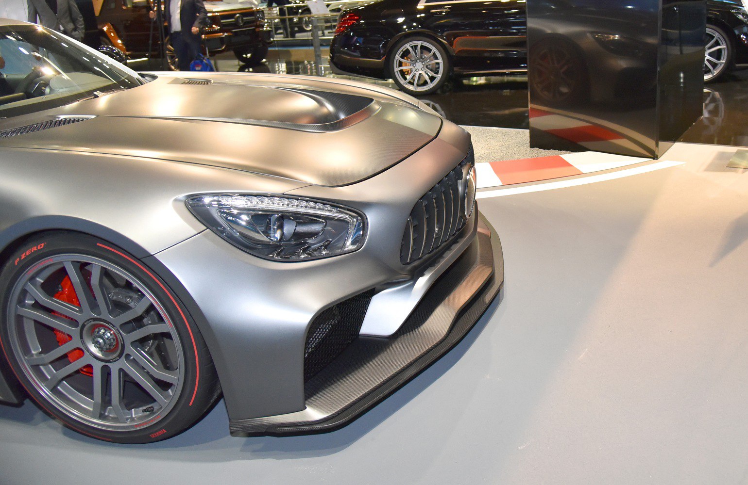 Close-up of front end with headlight and sporty wheel featuring red brake calipers.