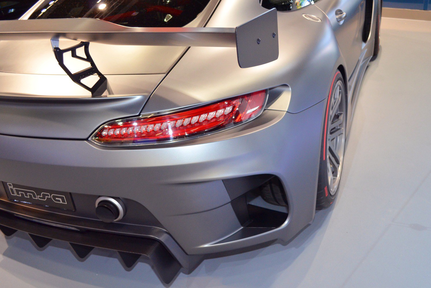 Rear LED taillight, large aero wing, rear diffuser, and racing tire.