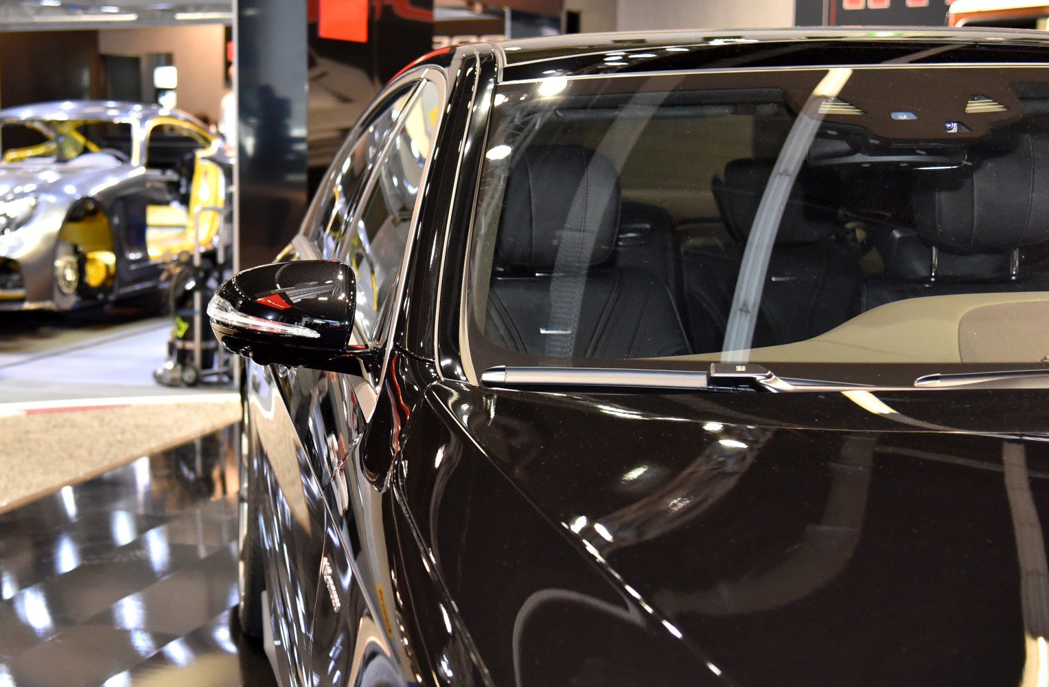 Close-up of side mirror and front windshield on black luxury sedan.