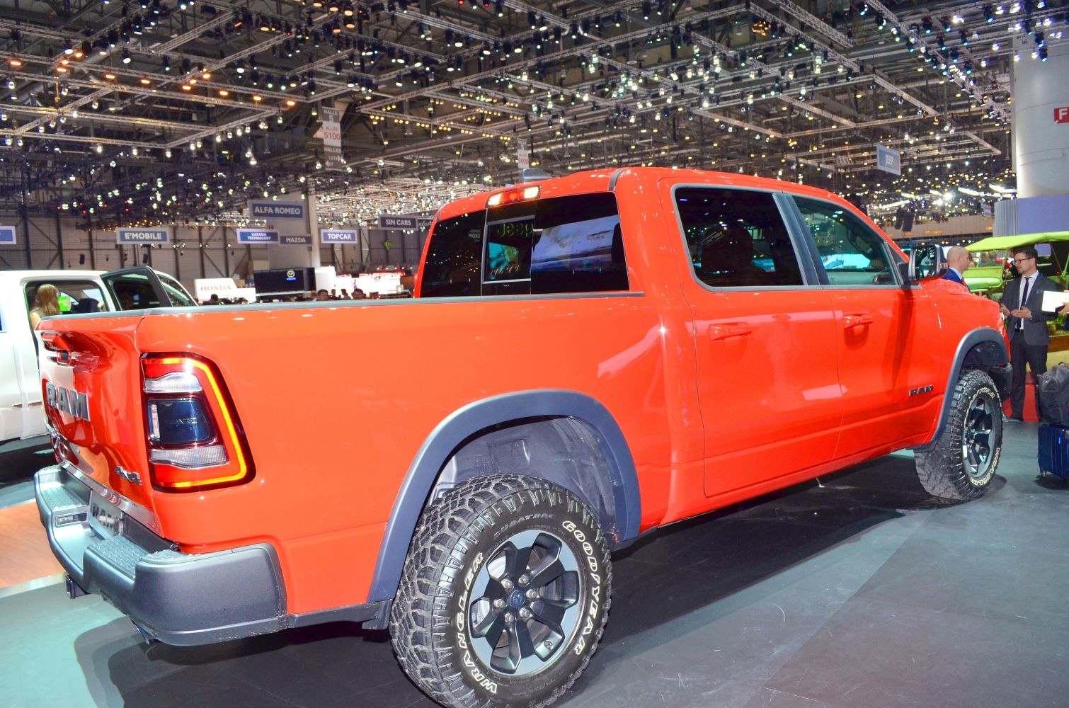 Rear side view of bright orange truck with off-road tires and crew cab configuration.
