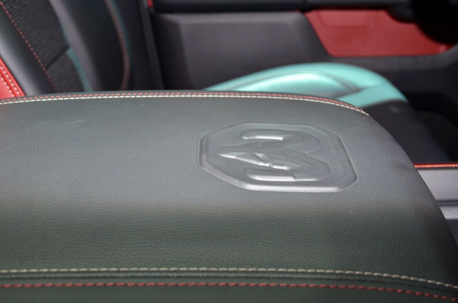 Close-up of embossed branding on leather upholstery with red and white stitching