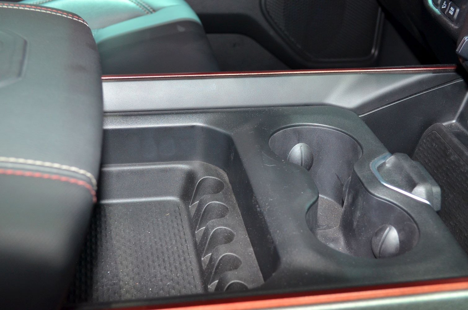 Vehicle interior storage console with cup holders and stitched leather armrest