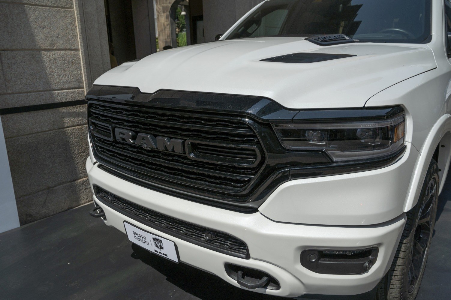 Close-up of bold black front grille and LED headlights on white pickup front.