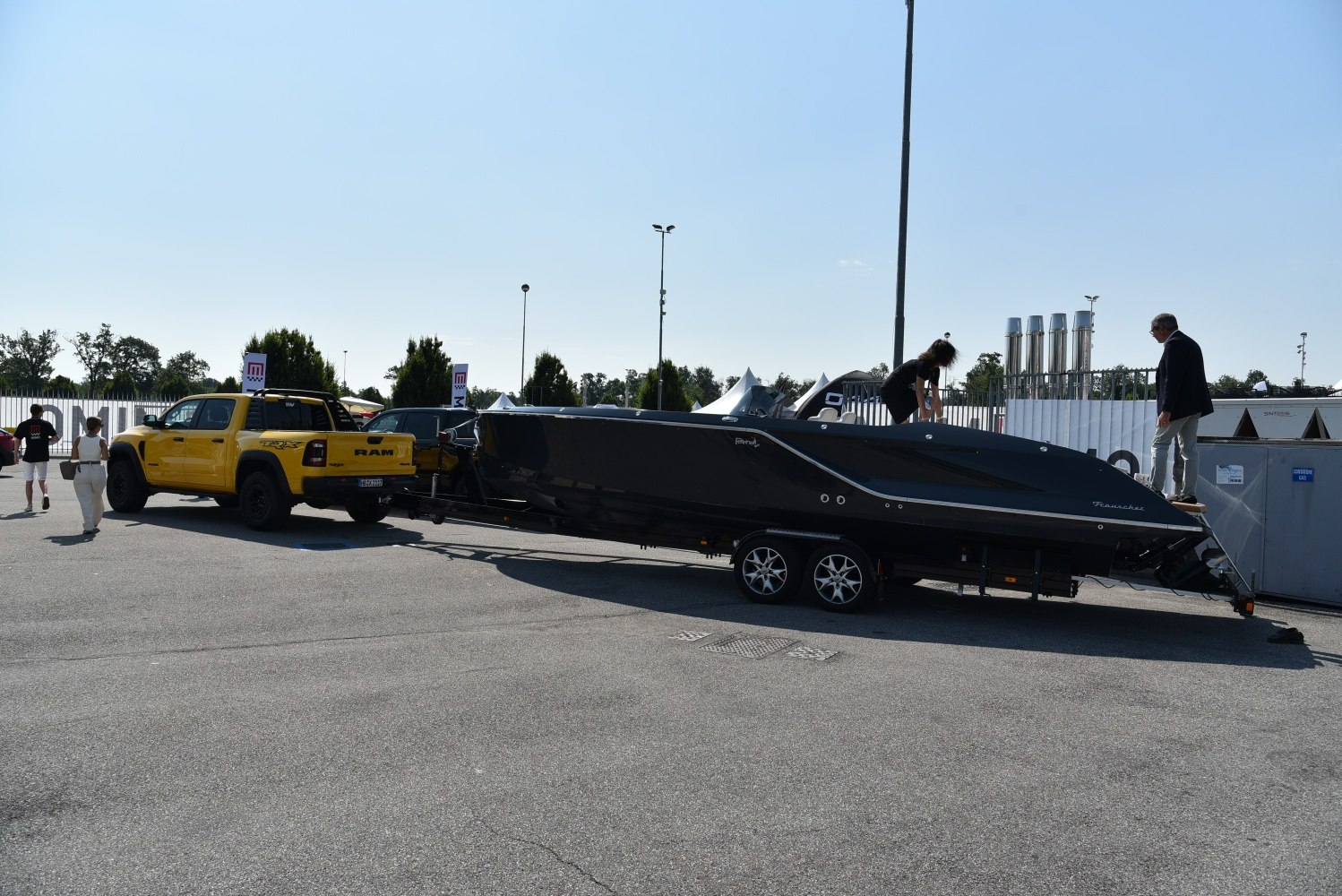 Truck towing large boat on dual-axle trailer.