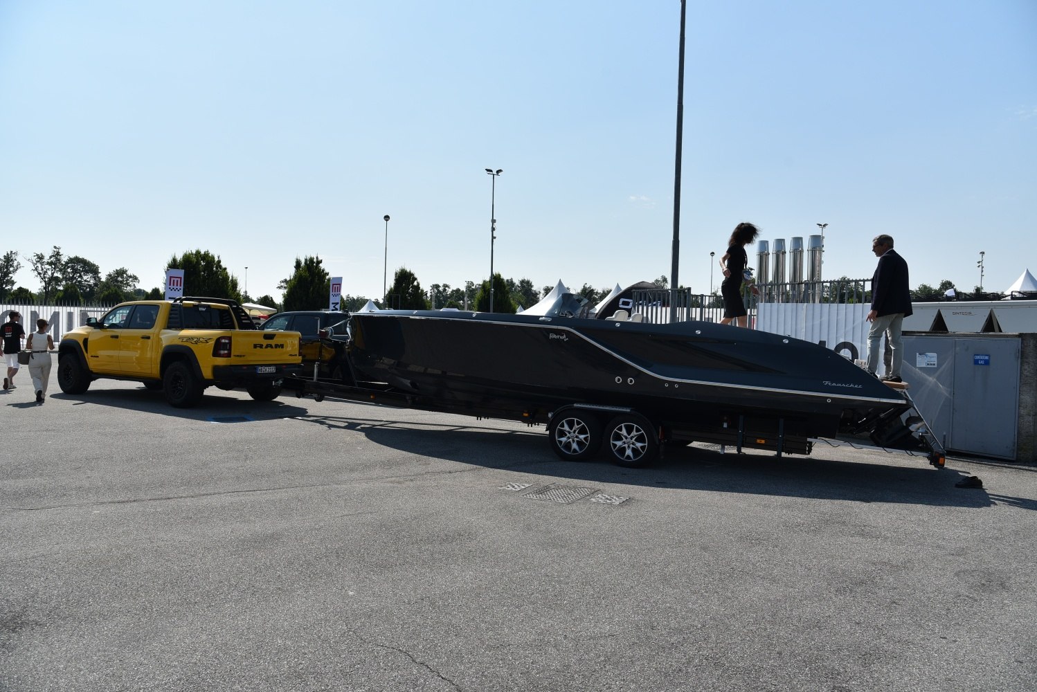 Yellow pickup towing a large black luxury boat on a twin-axle trailer