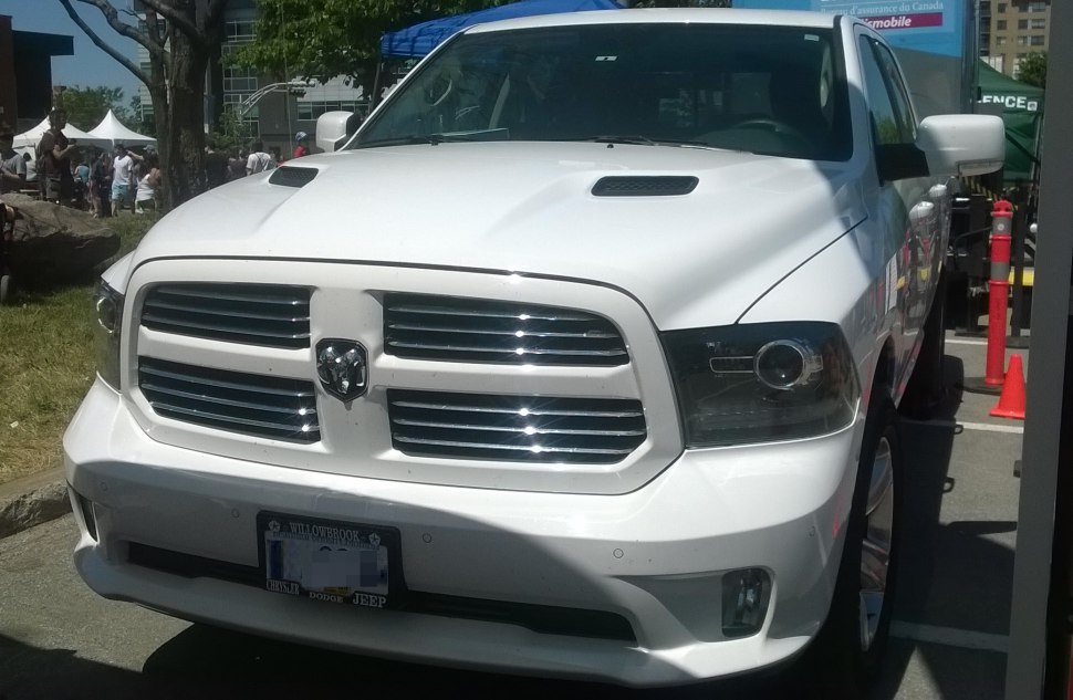 Closeup view of front grille and headlights of a white pickup truck.