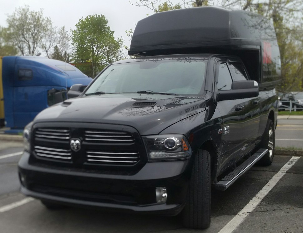 Black pickup with raised roof cargo box and LED headlights