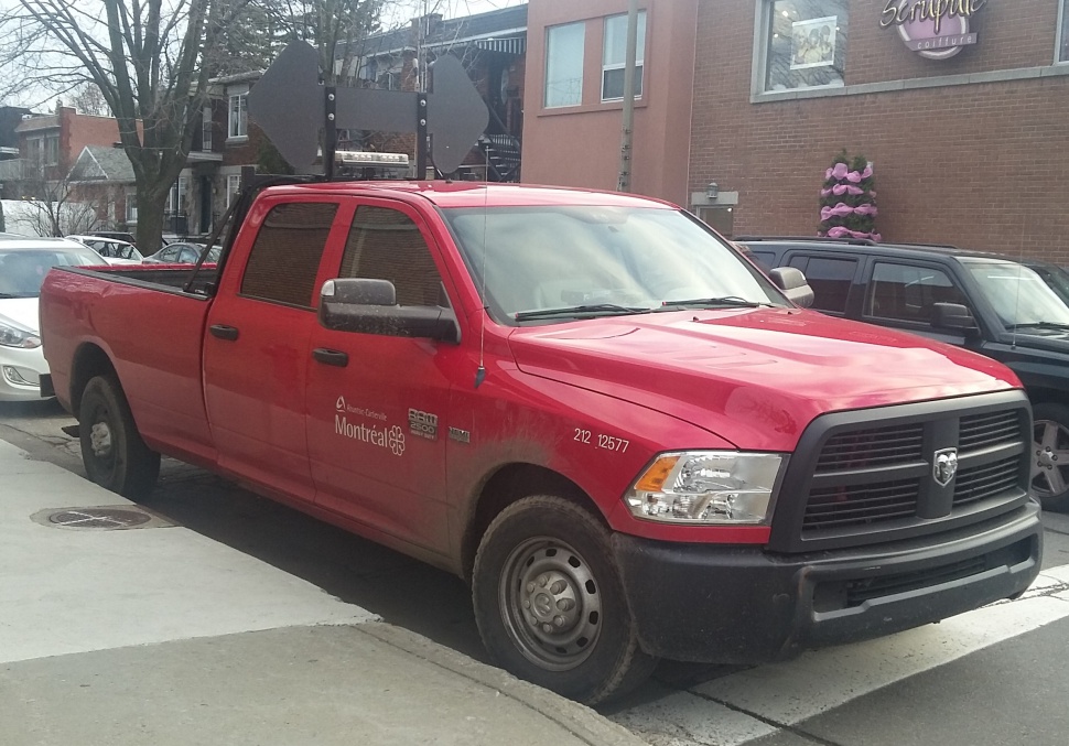 Heavy-duty red pickup truck with crew cab and black grille parked on street.