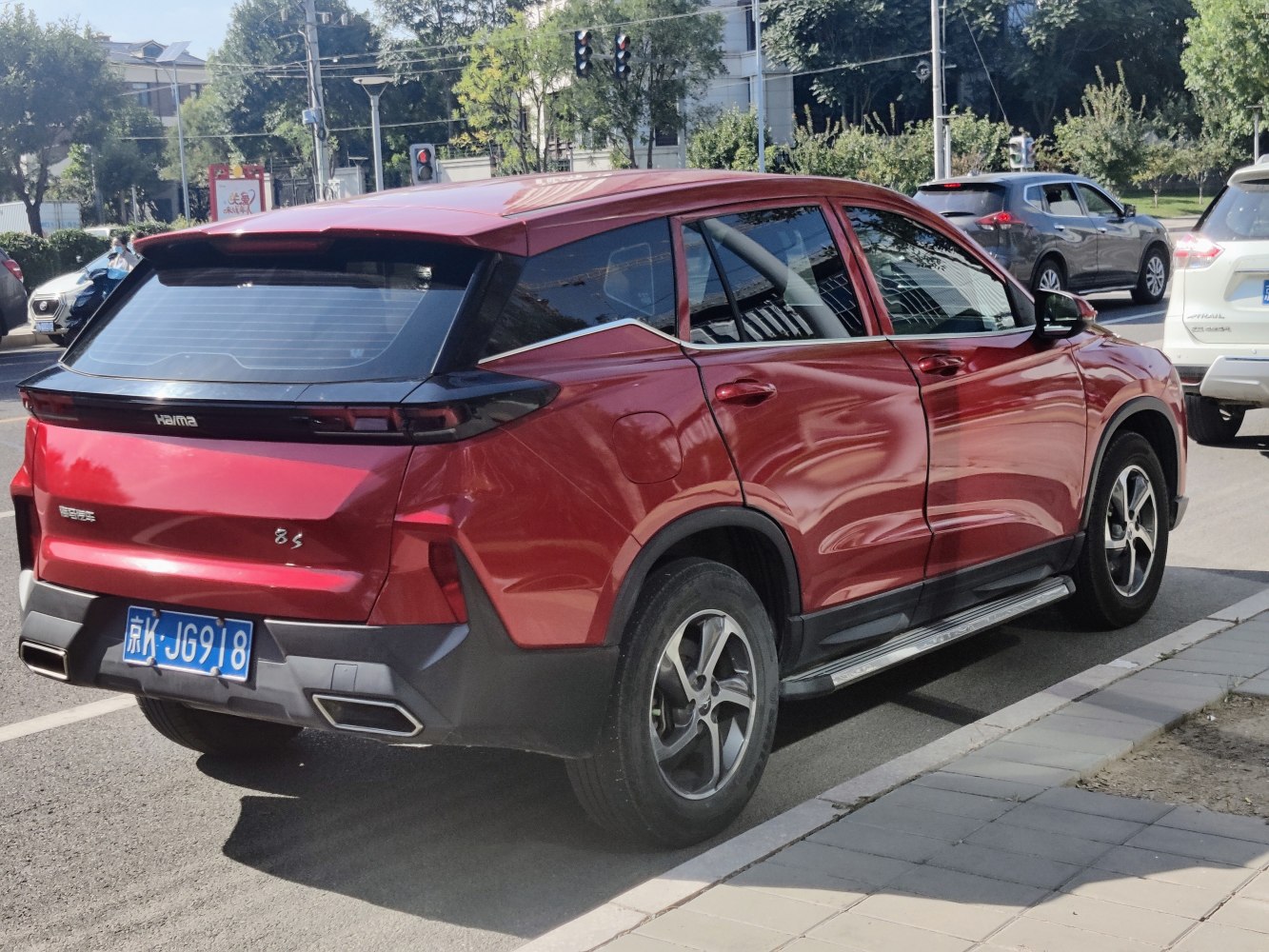 Rear and side view of a modern red SUV with sharp design lines and alloy wheels.