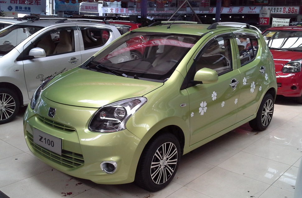 Light green small hatchback with floral decals and alloy wheels in showroom