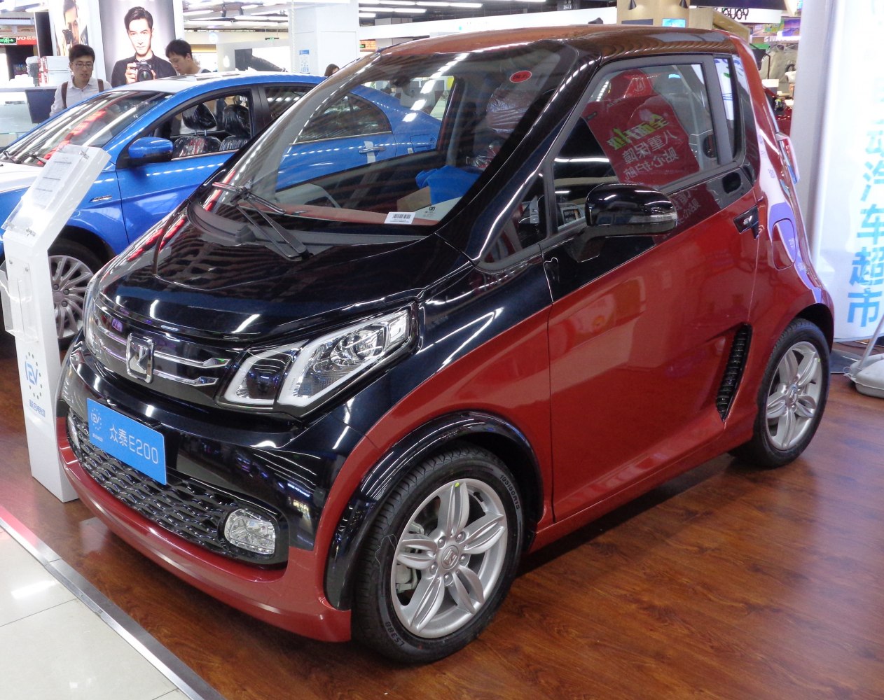 Compact two-tone electric urban vehicle with modern headlights and alloy wheels