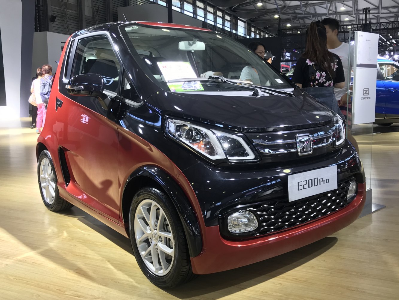 Two-tone compact electric vehicle front and side close-up with modern headlights and sporty grille