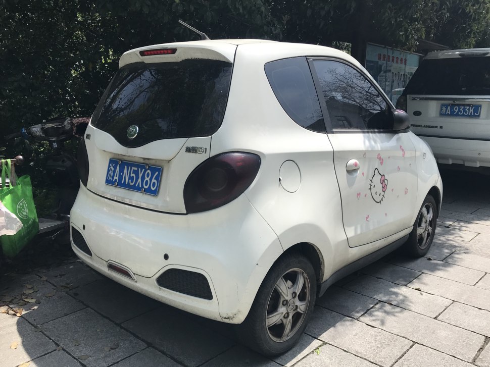 Compact white electric hatchback with tinted taillights and Hello Kitty decal on the door.