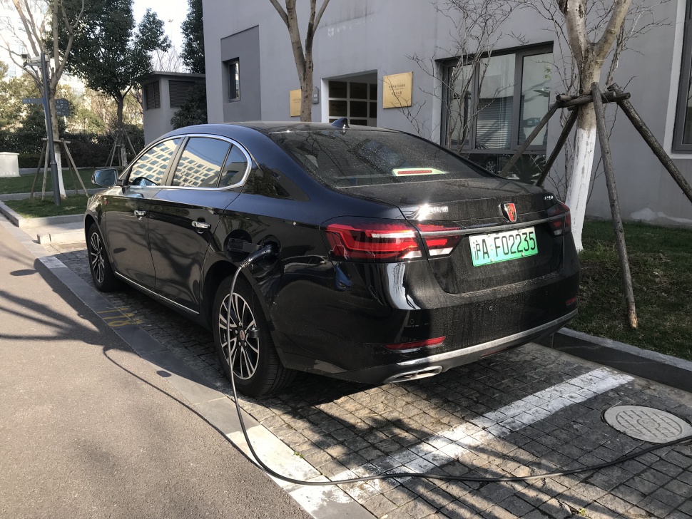 Rear view of a black sedan plugged in for charging