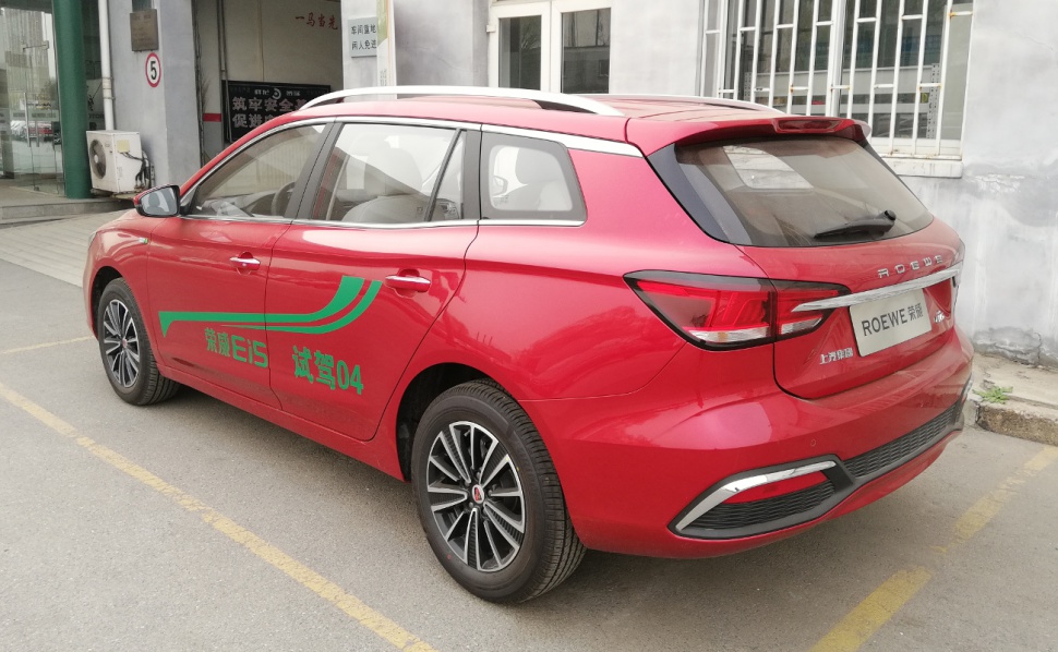 Red station wagon with rear and side design features, alloy wheels, and roof rails