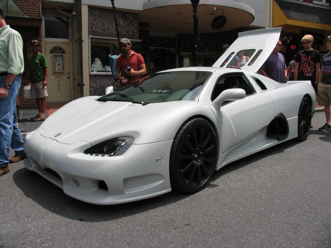 White supercar with open rear engine compartment and black wheels