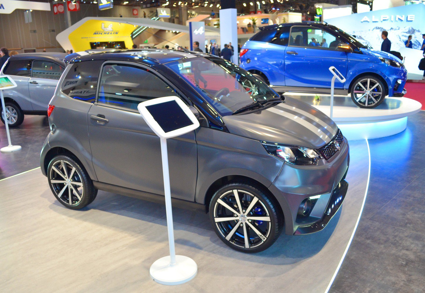 Compact two-door microcar with sporty alloy wheels and matte gray finish