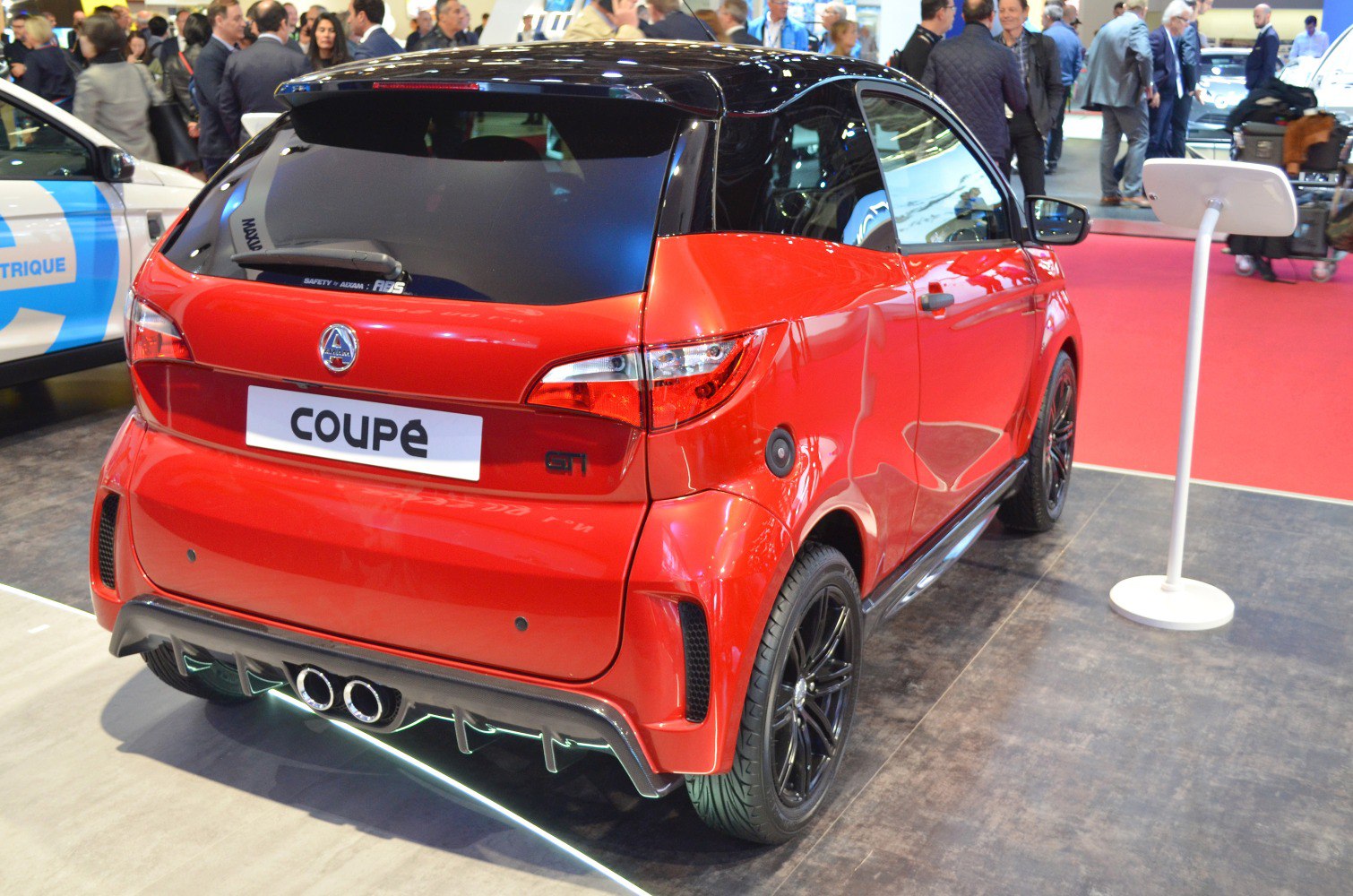 Rear view of red compact coupe with black wheels and dual exhaust
