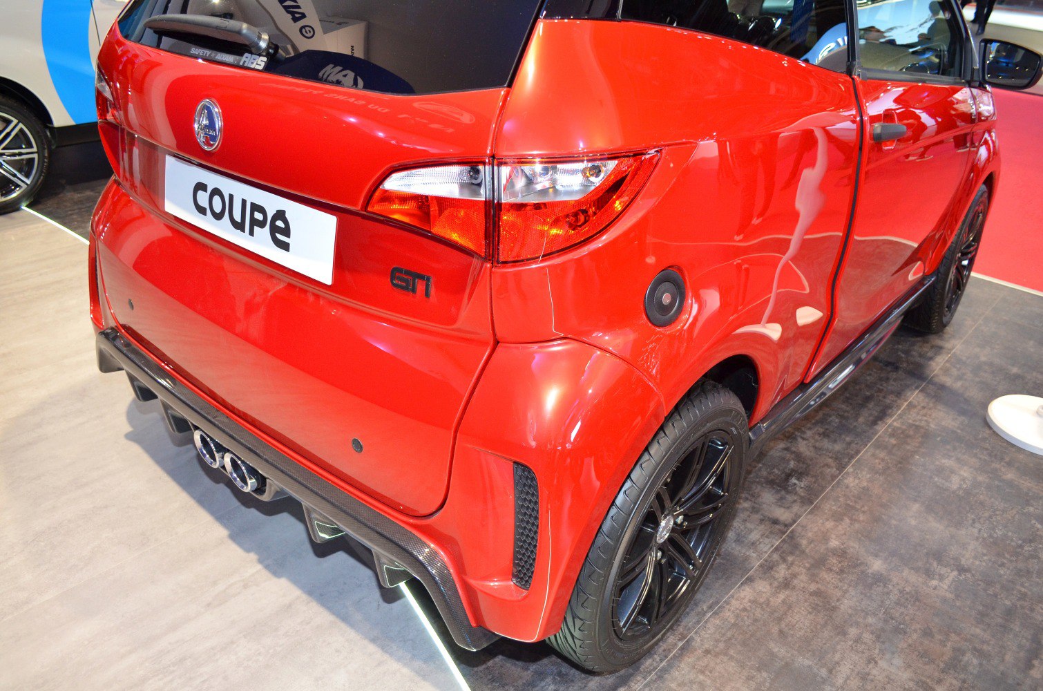 Rear view with taillights, dual exhaust, black wheels of compact coupe