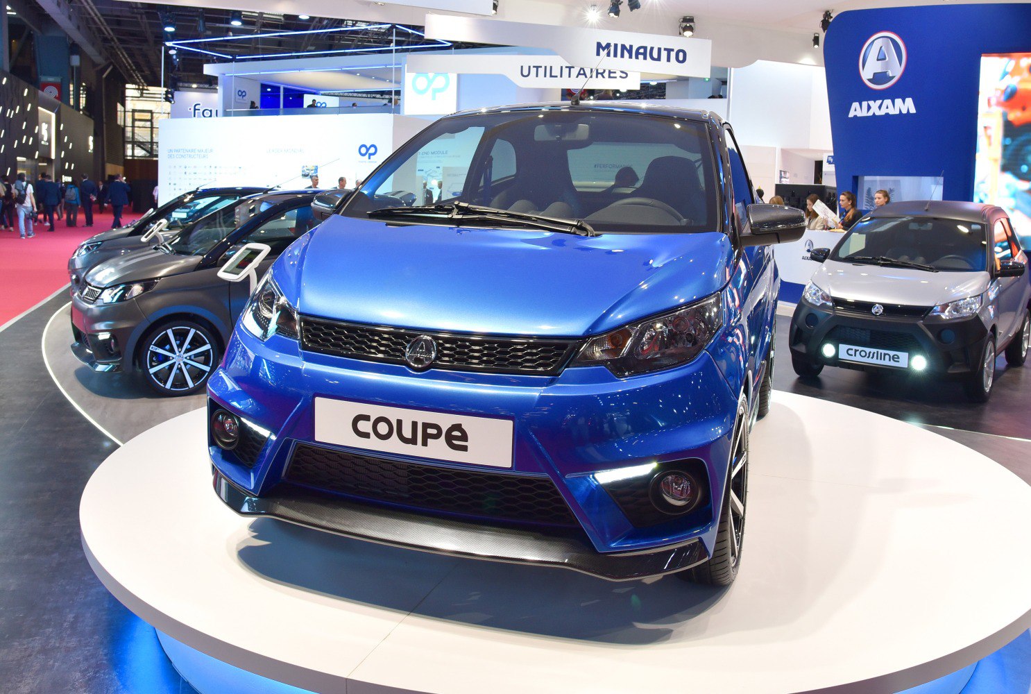 Front view of a blue microcar with sleek headlights and sporty grille