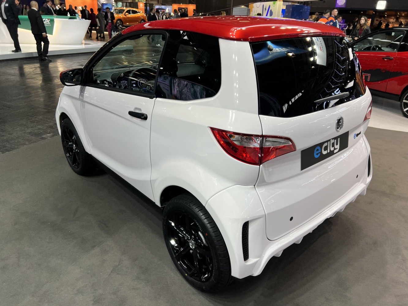 Electric microcar rear view with black alloy wheels and red roof