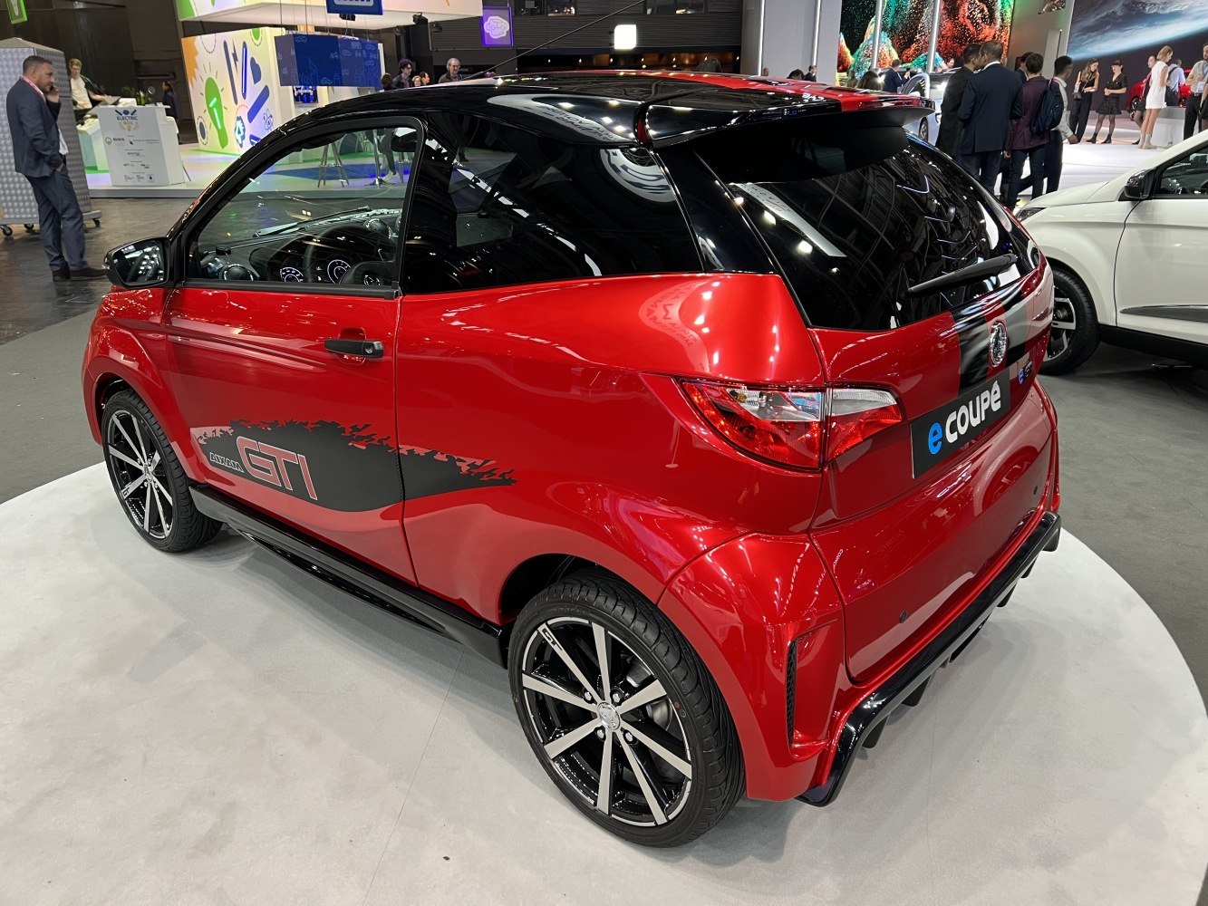 Red compact electric coupe with black roof and sporty rear design