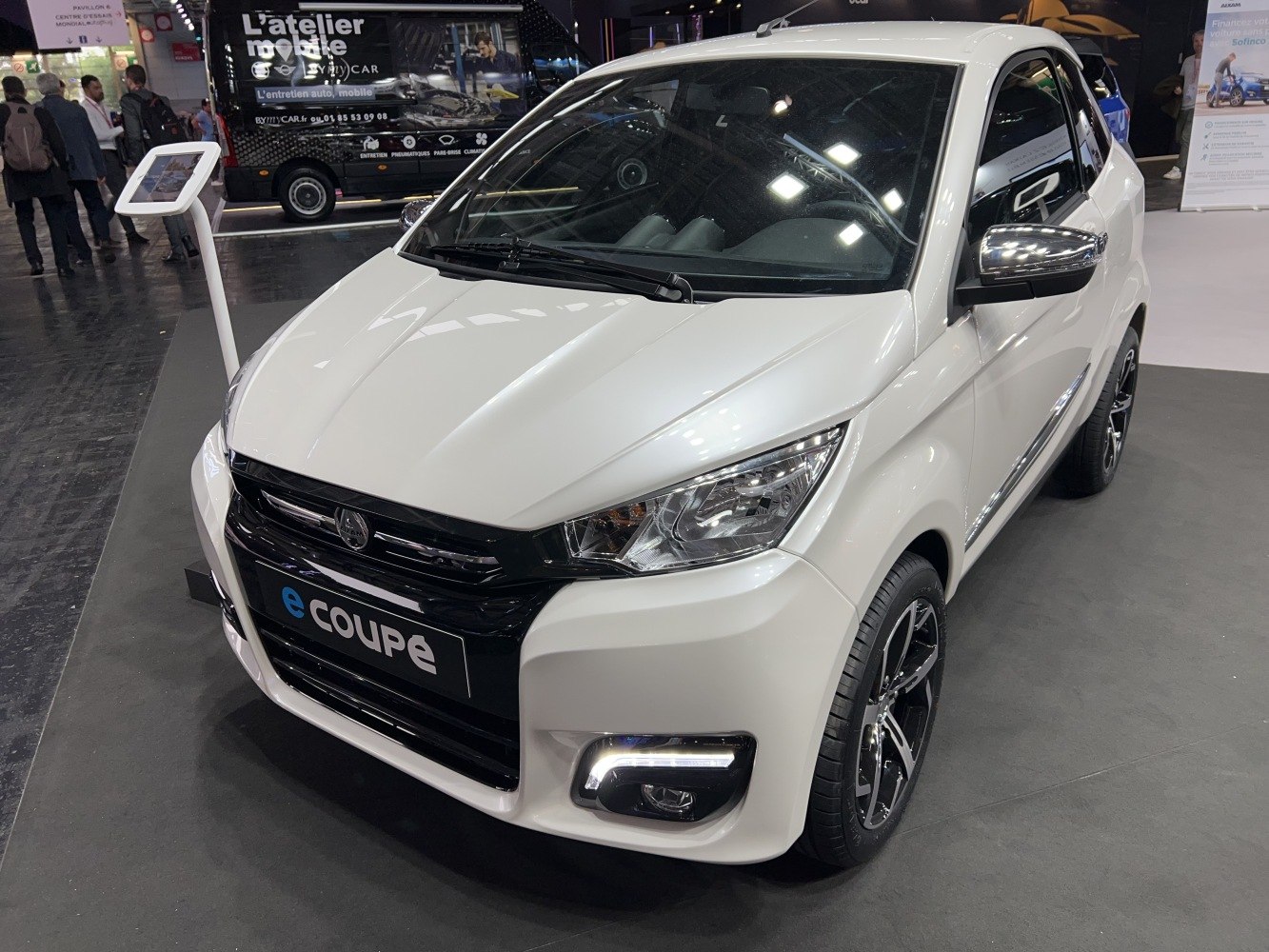 Compact electric vehicle front with sharp headlights and alloy wheels