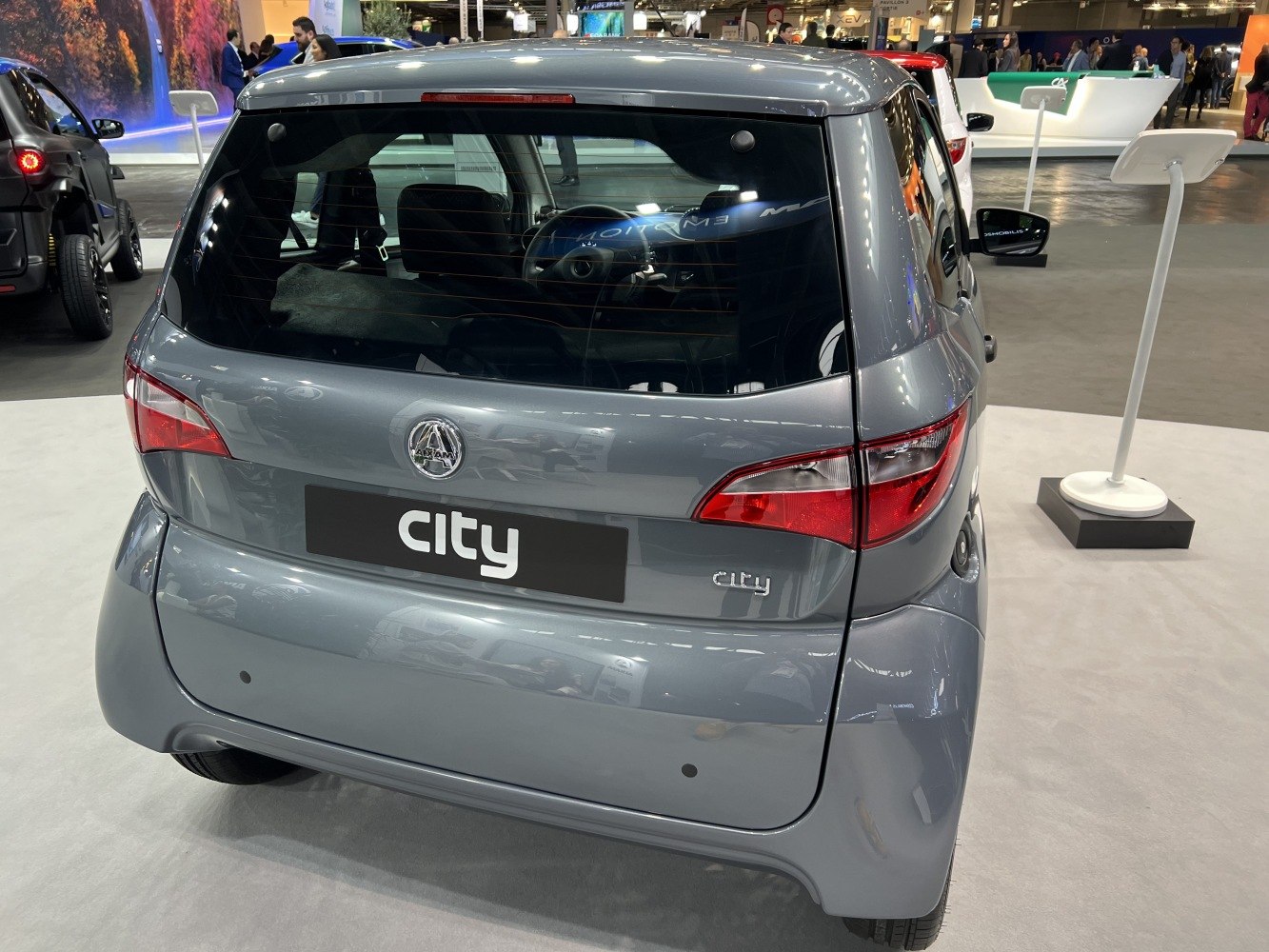 Compact electric vehicle rear with distinctive taillights and city badge.