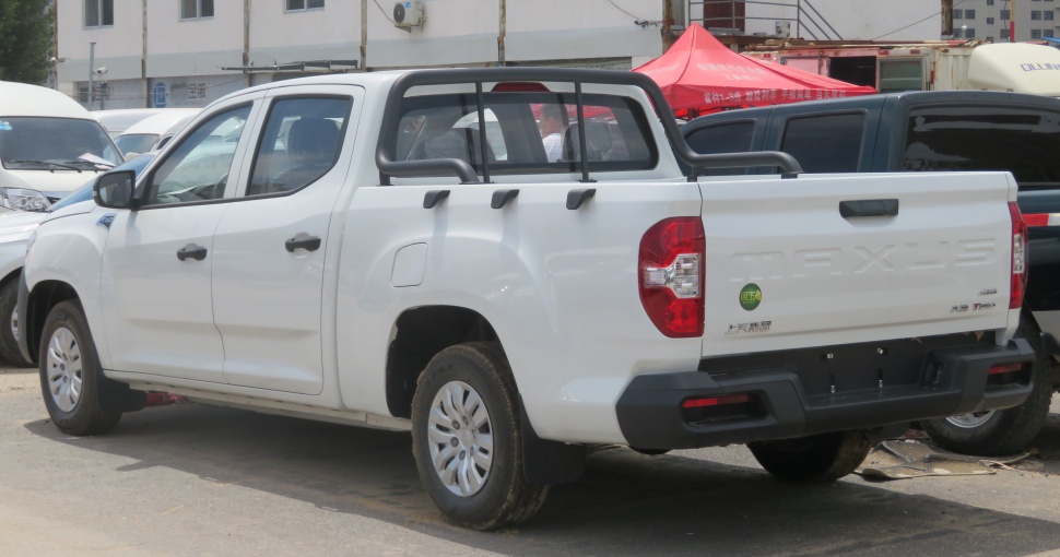 Rear and side view of a dual cab pickup truck with cargo bed and white body.