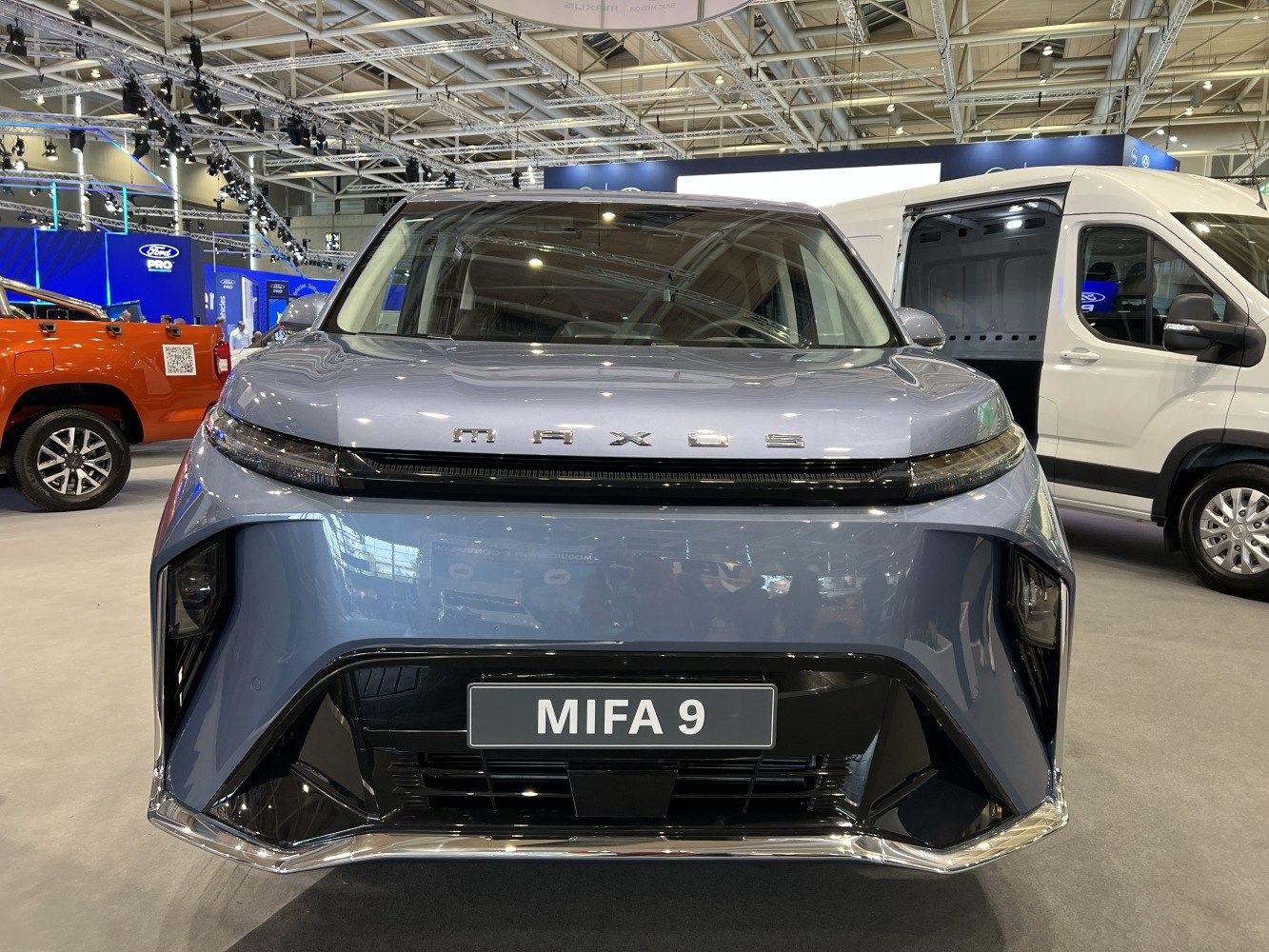 Front view of a modern electric MPV with slim LED headlights and bold grille design.