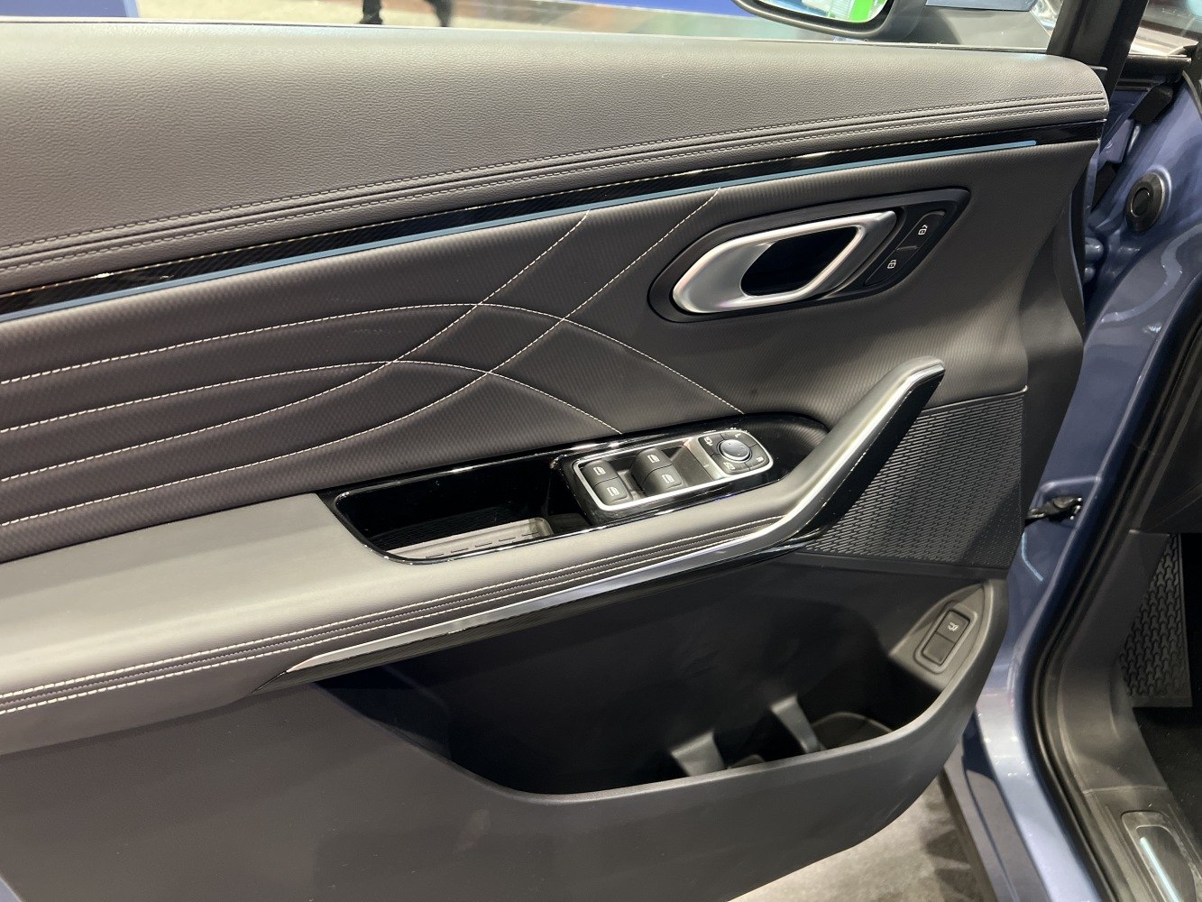 Close-up of door panel with window controls and stitched upholstery