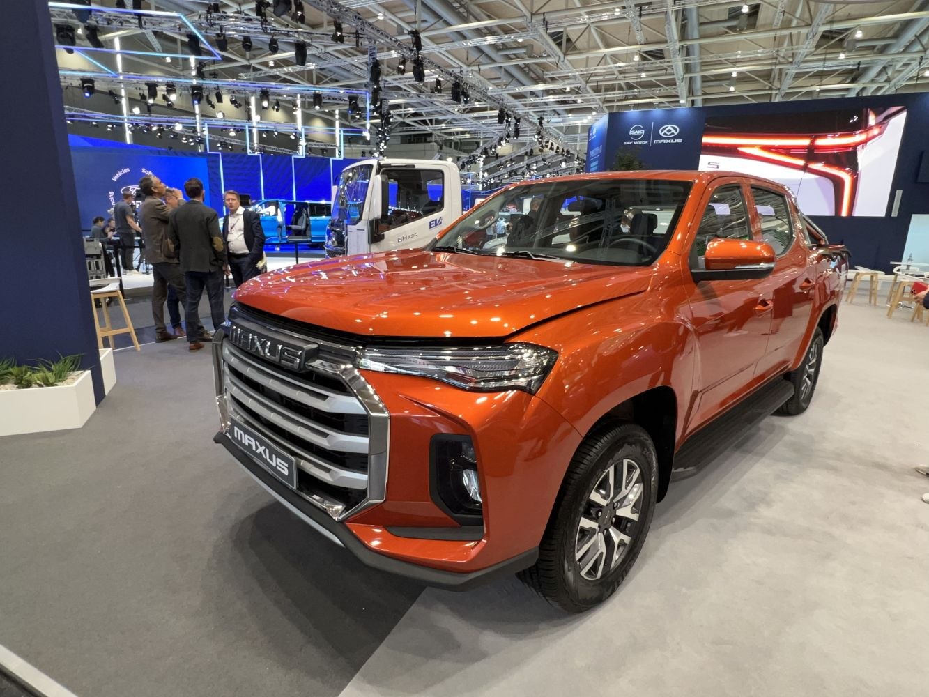 Bold grille and modern headlamps on orange pickup truck front.