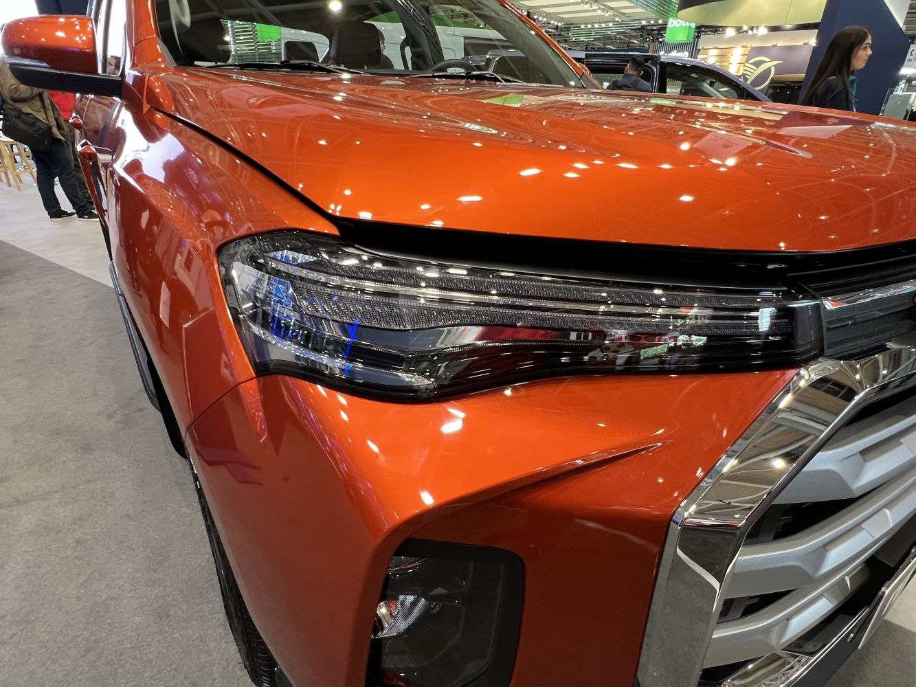 Close-up of front LED headlight and grille of an orange vehicle