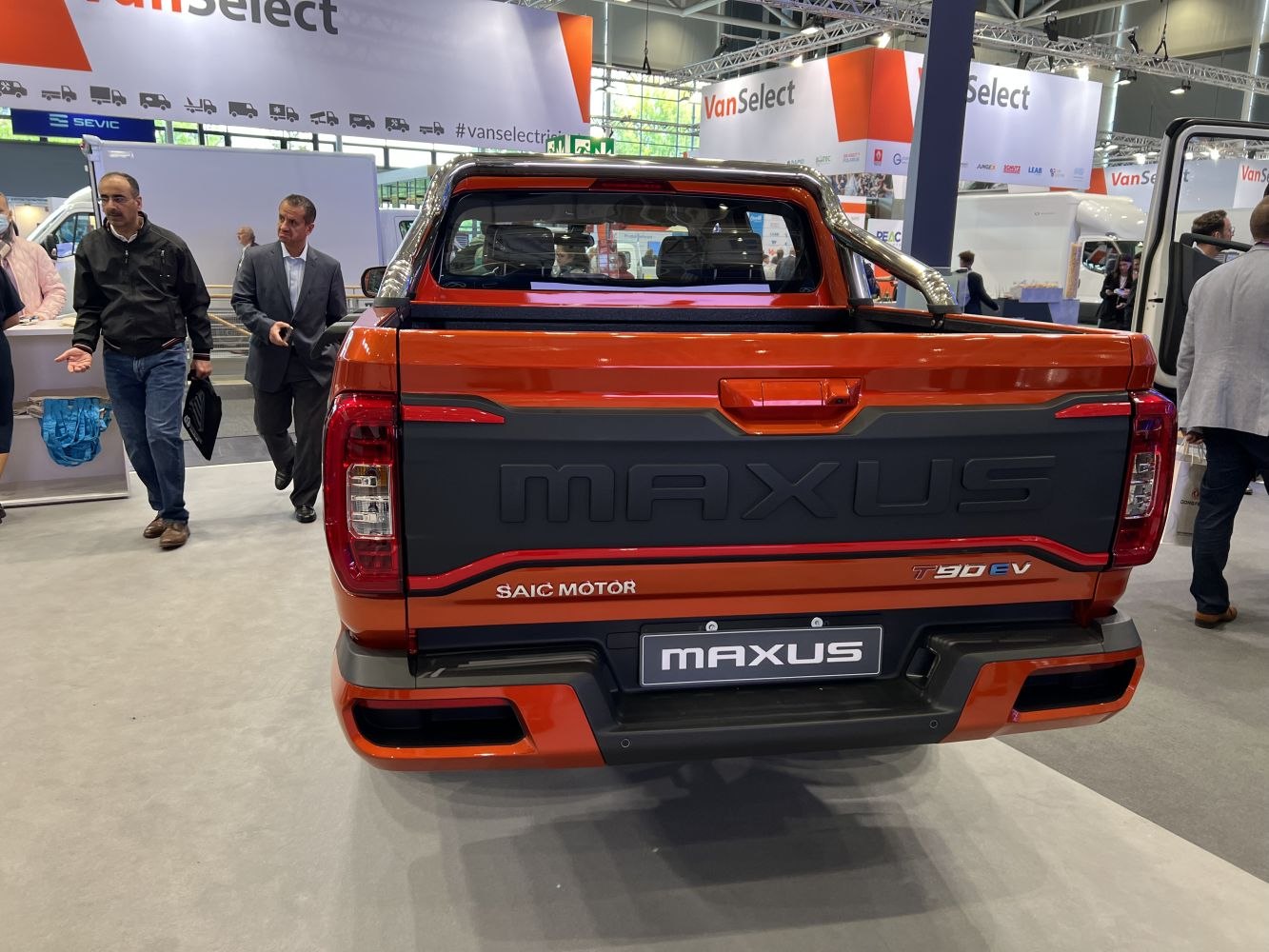 Electric pickup truck rear with bold Maxus branding and orange tailgate.