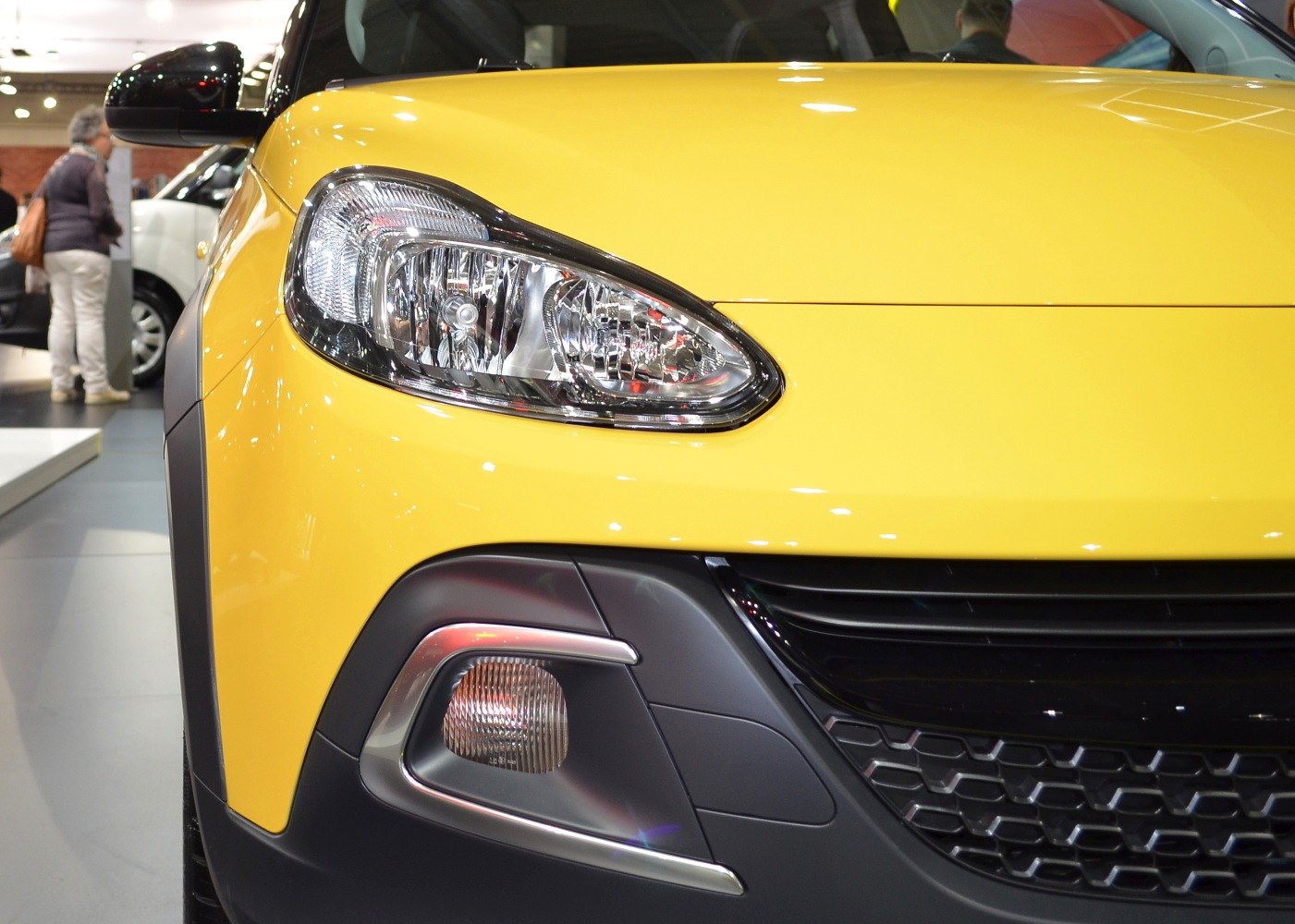 Front headlight and fog light close-up with black grille on yellow car.